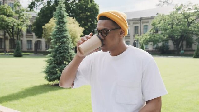 African American student sipping coffee sitting outdoor in the campus.