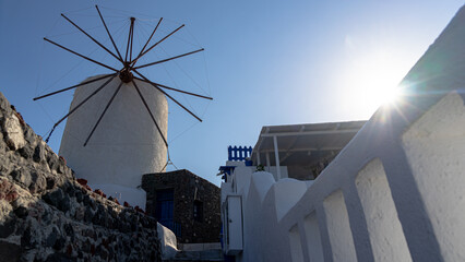 A view of Oia's iconic windmill with sun rays and lens flares