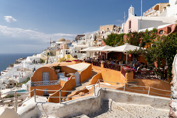 A view of iconic Oia on Santorini island with a colorful orange house in the foreground like in a...