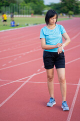 Choseup of Asian young woman tying shoes laces on athetic track in outdoor gym.