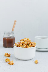 Fototapeta na wymiar Sweet caramel popcorn in a ceramic bowl on a gray background