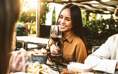 Happy asian woman drinking red wine sitting at restaurant dining table - Group of friends having...