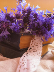 wedding bouquet of purple cornflowers with white vintage ribbon with blue books, boxes side view