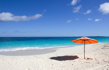  Red umbrella on white sand beach in Nassau, Bahamas