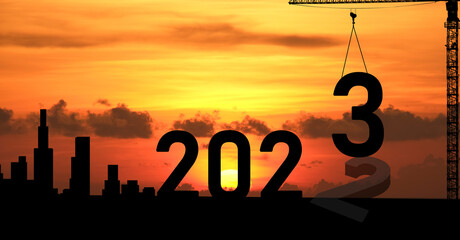 Concept Happy new year Silhouette of engineer and construction to create lifting crane 2023 on sunset background.