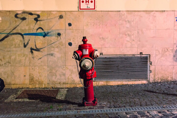 Red fire hydrant at night next to a building on the sidewalk