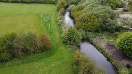 Aerial view looking down onto a river surrounded by large trees and green farmland. 