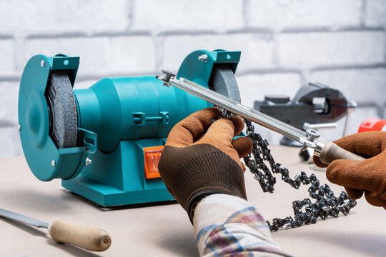 A man sharpening a chainsaw chain with file.
