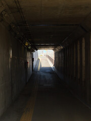 In the pitch-dark, long, eerie tunnel, see a bright exit on the other side.