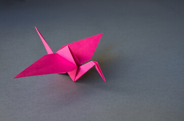 Pink paper crane origami isolated on a grey background