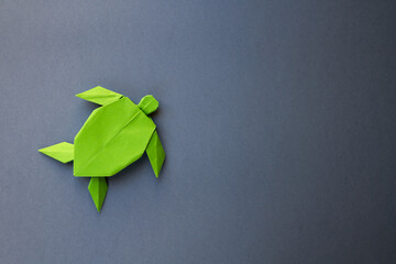 Green paper turtle origami isolated on a grey background - obrazy, fototapety, plakaty