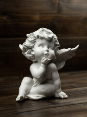 plaster white statuette in the form of an angel on a dark wooden background