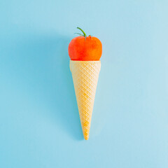 Tomato in ice cream cone isolated on blue background.  Abstract summer idea. Surrealism. 