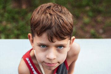 Obraz premium Sad slender boy 6-7 years old, top view, focus on the sad eyes of the boy. The boy needs to eat and sleep more to look healthy and happy