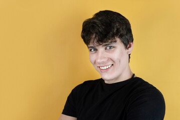 A young man, a teenager smiling with big eyes as if mocking, laughing at someone, on an orange background, the guy has a beautiful face and a little evil, with elements of bullying smile