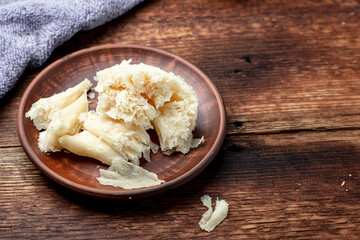 Hard cheese sliced chips on a clay plate on a wooden background.