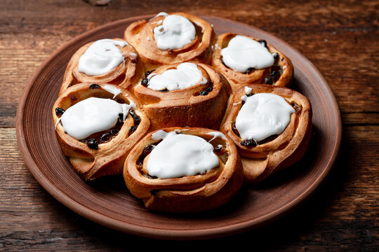 Buttery Sweet Buns With Raisins On A Brown Clay Plate. Covered With White Sugar Syrup.