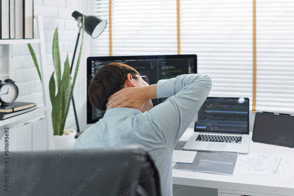 Wall mural software development concept, male programmer suffering neck pain after working hard on computer
