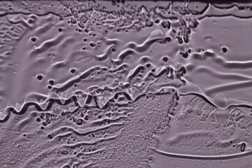 Water drops, streaks on the glass on a purple background