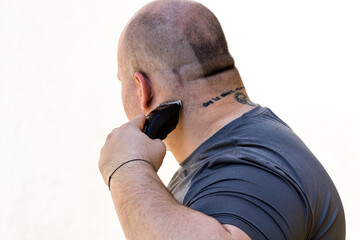 Male shaving or trimming his hair using a hair clipper or electric razor