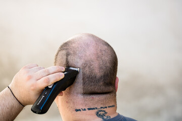 Male shaving or trimming his hair using a hair clipper or electric razor