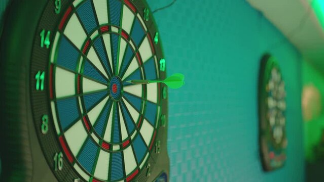 The dart arrow hitting the center . Three darts hit the target of a dart board . Good shots on target of a dart board .  A close-up of a dartboard with darts thrown into it . Shot on ARRI ALEXA camera