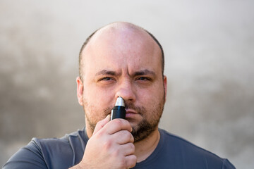 Male shaving ortrimming his nose hair using a hair clipper or electric razor