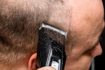 Man shaving or trimming his hair using a hair clipper