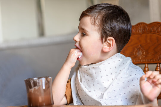 a little boy eats with his hands and is covered in food