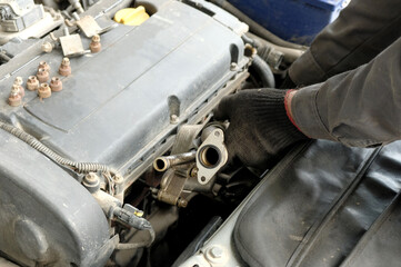 Repair of internal combustion engines. The car mechanic holds in his hands and installs the engine heat exchanger.