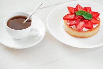Strawberry tart, cake, and mug with black coffee on white board background, selective focus.