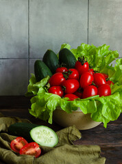 Cherry tomatoes, cucumbers and lettuce leaves in kitchen interior.