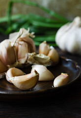 Garlic cloves with green onion on a dark wooden table.