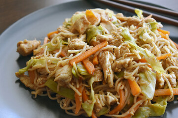 Chicken chow mein on a black plate.  Traditional Chinese food. 