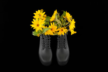 Black women platform boots with bouquet of yellow Jerusalem artichoke flowers, black background