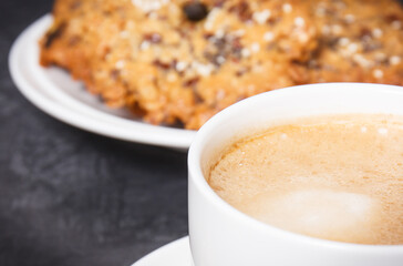 Cup of coffee with milk and fresh baked oatmeal cookies on plate. Delicious crunchy dessert