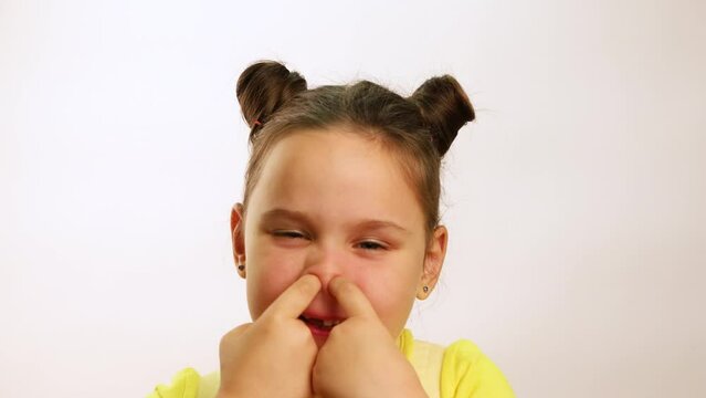 Little funny girl wide smiling with gap in mouth from fallen tooth and picking nose with both hands closeup, white background. Joyful toothless child. Concept of healthy teeth and beautiful smile.