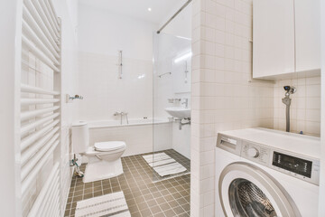 White bath and toilet, with a sink next to a glass partition in a bathroom with a washing machine