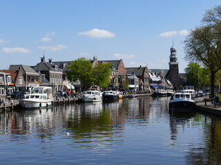 Fototapeta na wymiar The wide canal running through (Dutch) Lemmer (Frisian) De Lemmer, Friesland, Netherlands, is popular with leisure boaters and tourists alike, with numerous restaurants and shops on both sides