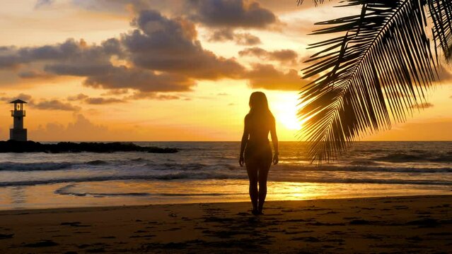 Attractive girl walking on sandy beach near palm tree branch with sea, sunset sun, lighthouse on background. Young woman silhouette enjoy summer holidays. Travel, tourist, vacations outdoors concepts.