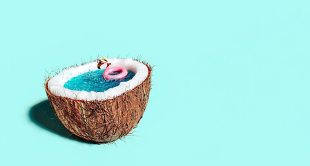 Half of coconut filled with water and pink flamingo inflatable belt. Summer vacation concept...
