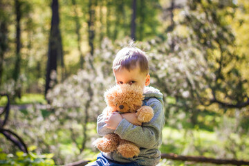 A cute boy is playing with a bear cub in the forest. The sun's rays envelop the space of the clearing with a stump. A magical story of interactions for the book. Space for copying. Selective