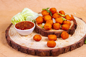 Fried fish or chicken popcorn isolated on wooden background. with Barbecue Sauce