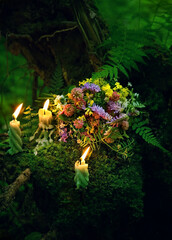 wildflowers with burn candles in mysterious forest, dark natural blurred background. Summer...