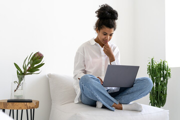 African american girl sitting on sofa with laptop