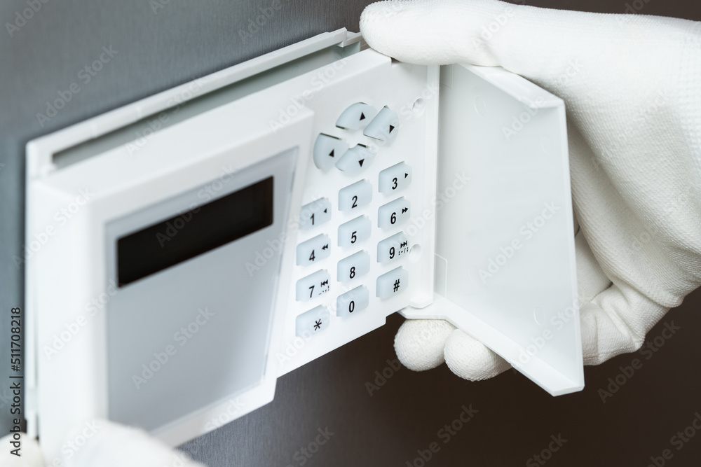 Poster installing a security systems keyboard on a gray wall.