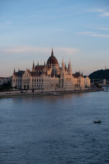 Fototapeta premium A boat fishing at sunset in the Danube in front of the Parliament of Budapest. Dreamy Sunset