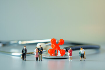 selective focus of red virus on black stethoscope and miniature people with mask on white ground to solution for Annual Health Check up.