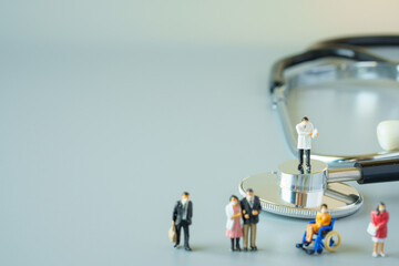 selective focus of miniature doctor on black stethoscope and miniature people with mask on white...