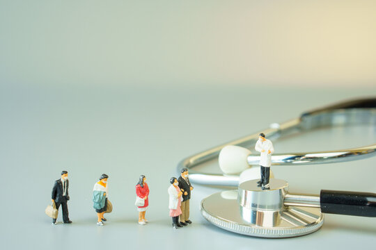 Selective Focus Of Miniature Doctor On Black Stethoscope And Miniature People With Mask On White Ground To Solution For Annual Health Check Up.